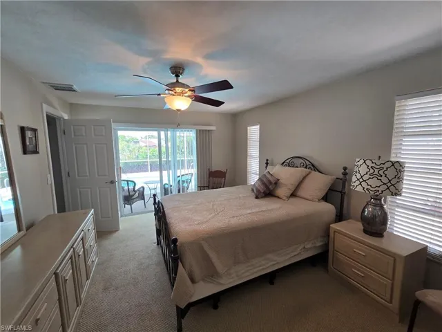 Bedroom with access to exterior, light colored carpet, and a ceiling fan