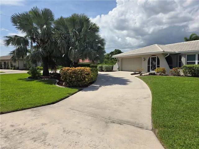 View of front of house featuring driveway, stucco siding, a front yard, an attached garage, and a tile roof