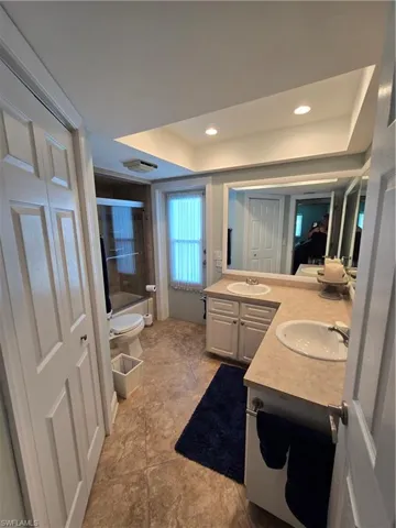 Common Bathroom with access to pool area a raised ceiling, vanity, a shower, a bathtub, and recessed lighting