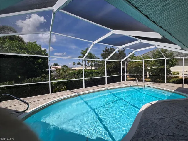 Swimming pool featuring a patio and glass enclosure
