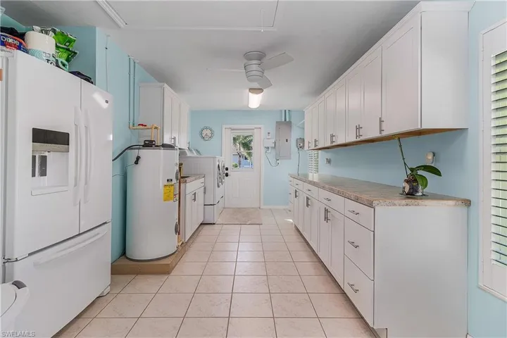 Oversized laundry room with access to the yard. Utility sink,refrigator, large custom cabinetry,wall ironing board.
