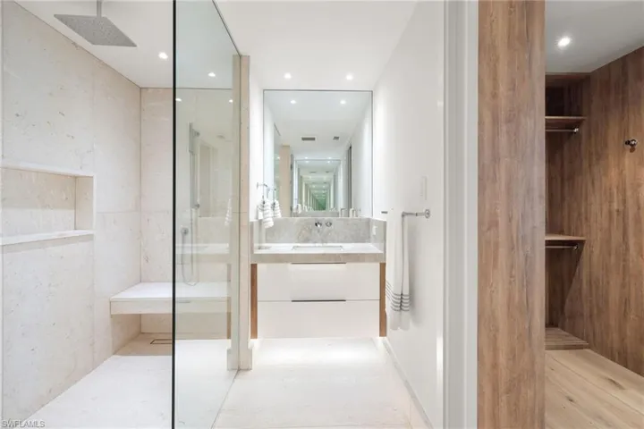 Bathroom with a walk in closet, vanity, a marble finish shower, and recessed lighting