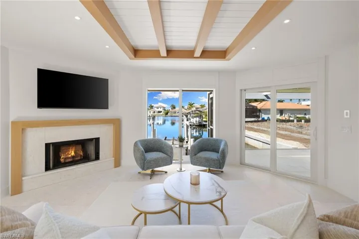 Living room with beam ceiling, recessed lighting, and a premium fireplace