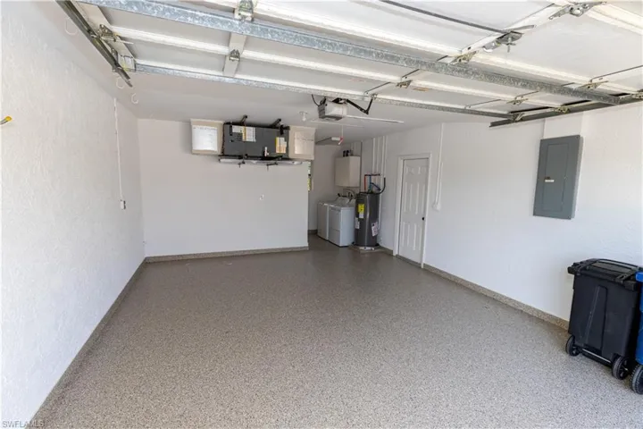 Garage with washer and clothes dryer, a garage door opener, and water heater