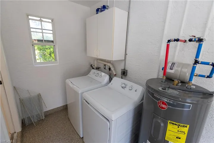 Laundry area featuring hookup for a washing machine, electric dryer hookup, water heater, washer and clothes dryer, and cabinets