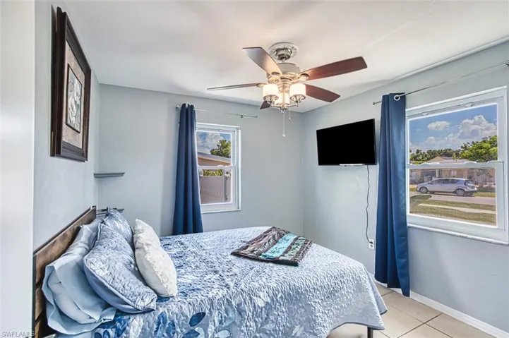 Bedroom featuring light tile patterned floors, ceiling fan, and baseboards