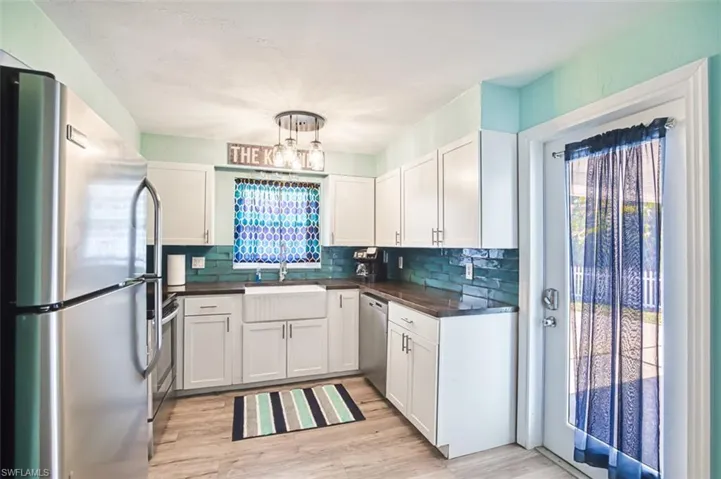 Kitchen featuring stainless steel appliances, a sink, dark countertops, and decorative backsplash