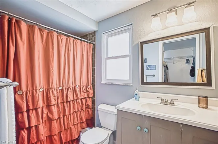 Full bathroom featuring toilet, vanity, and curtained shower