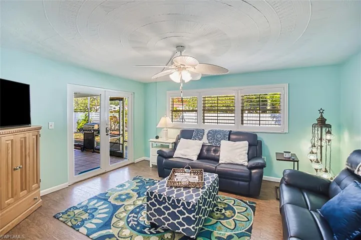 Living area with french doors, ceiling fan, baseboards, and wood finished floors