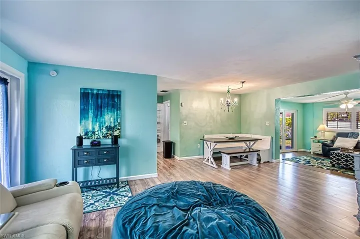Living room with wood finished floors, a chandelier, baseboards, and a ceiling fan