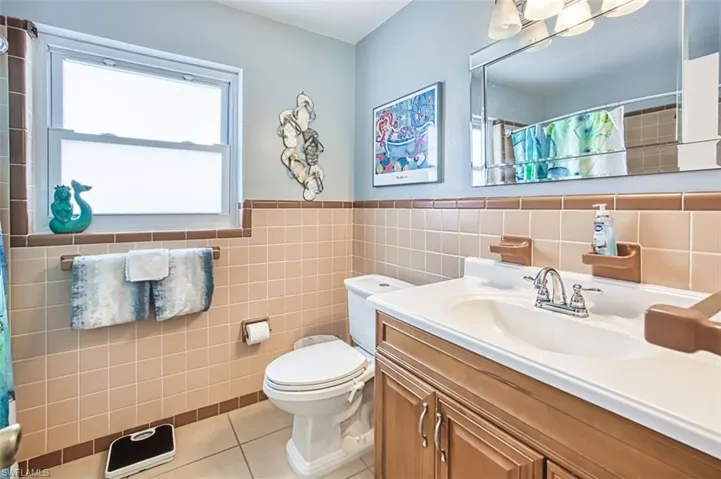 Full bath with tile patterned flooring, tile walls, vanity, a shower with shower curtain, and toilet