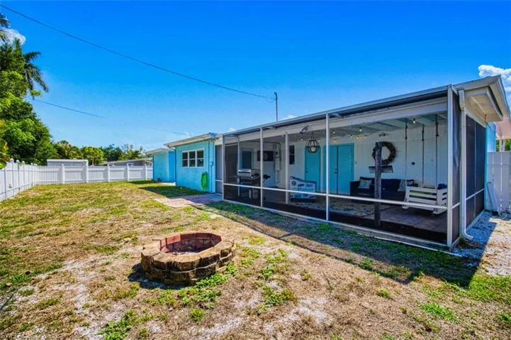 Back of house featuring an outdoor fire pit, a sunroom, and a fenced backyard