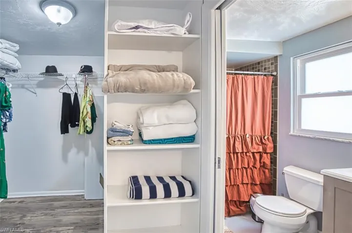 Bathroom with toilet, wood finished floors, vanity, and a shower with shower curtain