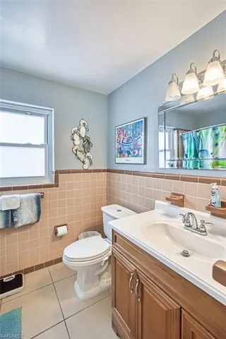Full bathroom featuring tile patterned flooring, vanity, tile walls, toilet, and wainscoting