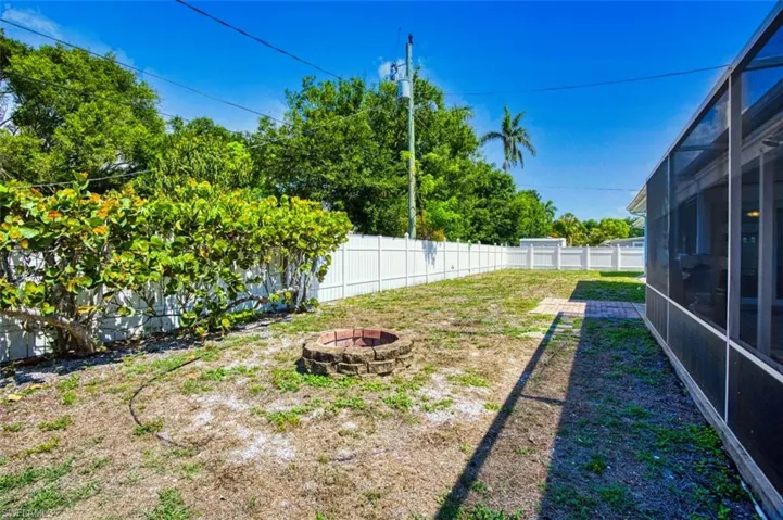 Fenced backyard with a fire pit and a lanai