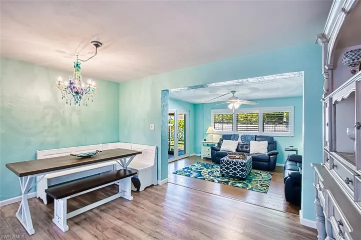 Dining space featuring wood finished floors, ceiling fan, baseboards, and a chandelier