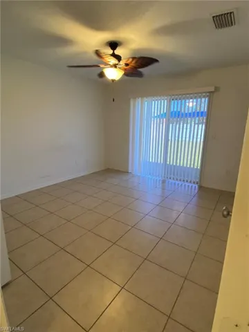 Tiled Master bedroom with ceiling fan and sliding glass to back yard.