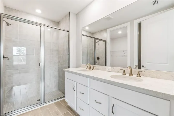 Full bath with a spacious closet and a shower stall