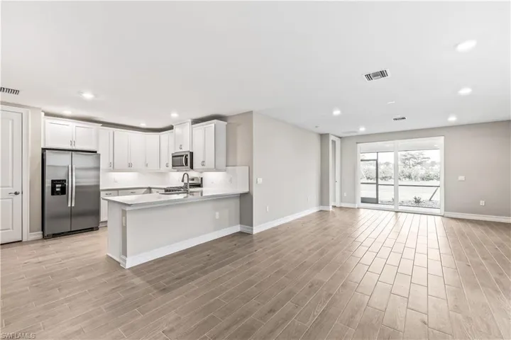 Kitchen with stainless steel appliances, open floor plan, white cabinetry, recessed lighting, and a peninsula
