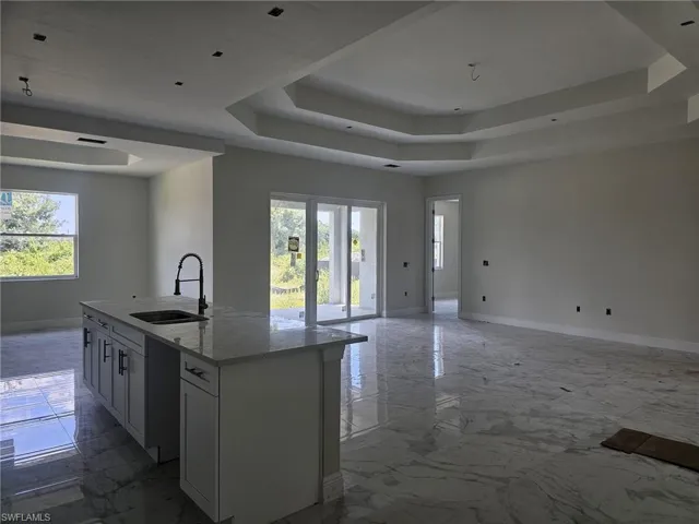Kitchen with an island with sink, sink, tile flooring, and a wealth of natural light