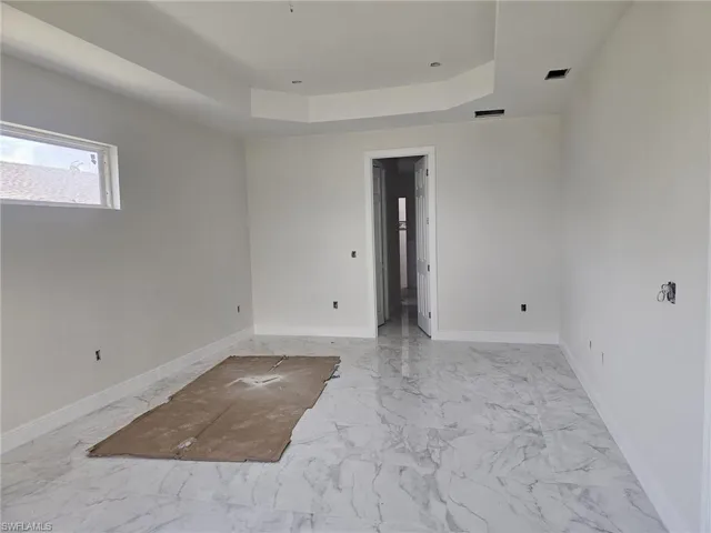Empty room with a tray ceiling and light tile flooring