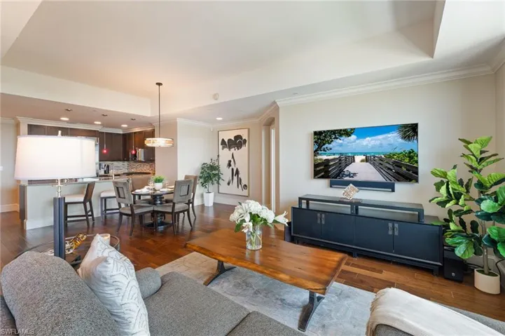 Living area with ornamental molding, dark wood-style flooring, a raised ceiling, and recessed lighting