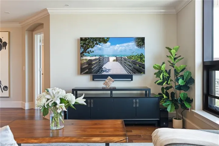 Living area featuring crown molding, wood finished floors, and arched walkways