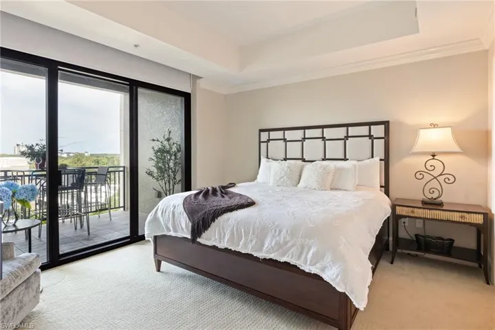 Carpeted bedroom with access to exterior, ornamental molding, and a tray ceiling
