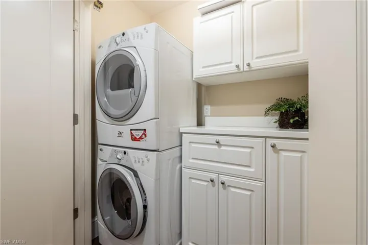 Laundry Area featuring stacked washing machine and dryer and built-in cabinets