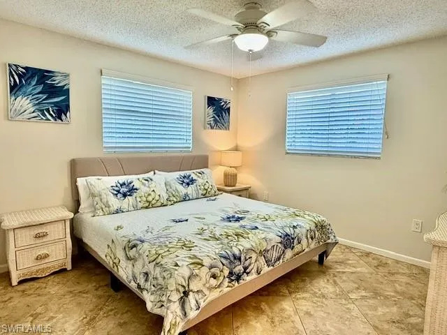 Bedroom with a ceiling fan and a textured ceiling