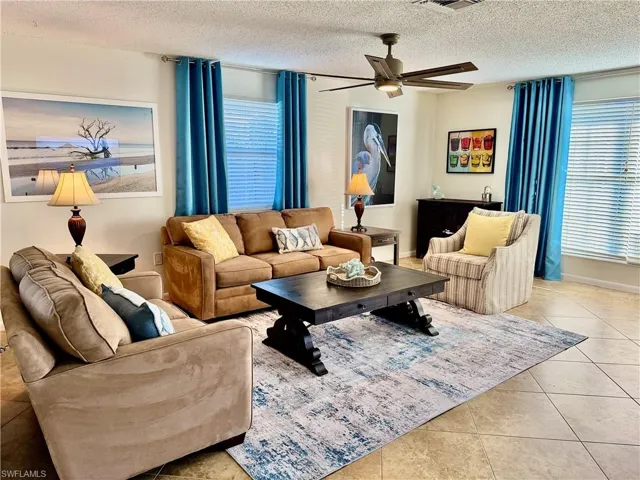 Living area featuring light tile patterned flooring, a textured ceiling, and ceiling fan