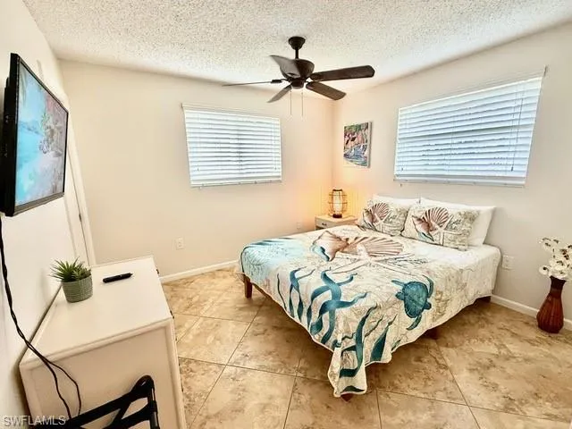 Bedroom with a ceiling fan and a textured ceiling