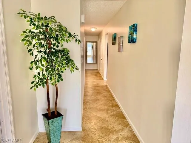 Corridor featuring a textured ceiling and light tile patterned floors
