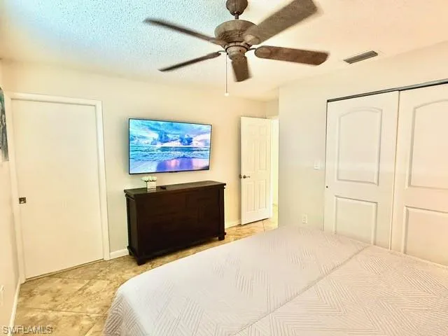 Bedroom with a textured ceiling, a ceiling fan, and a closet