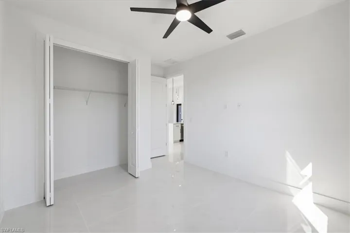 Unfurnished bedroom with ceiling fan and a closet