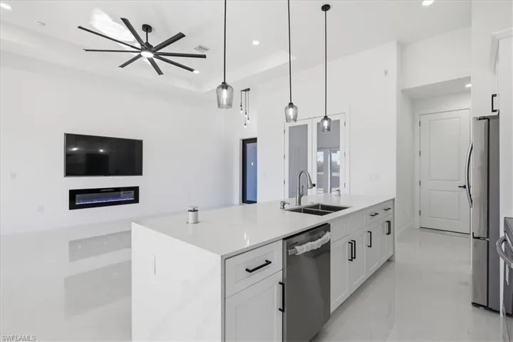 Kitchen with a center island with sink, white cabinetry, light stone countertops, stainless steel appliances, and open floor plan
