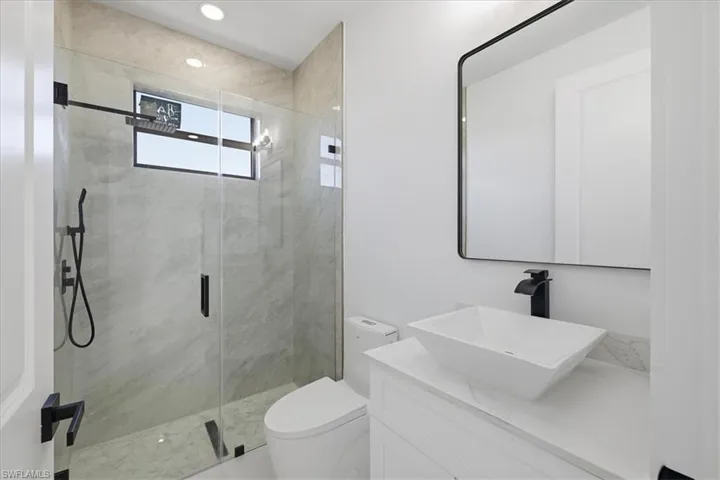 Bathroom featuring a marble finish shower and vanity