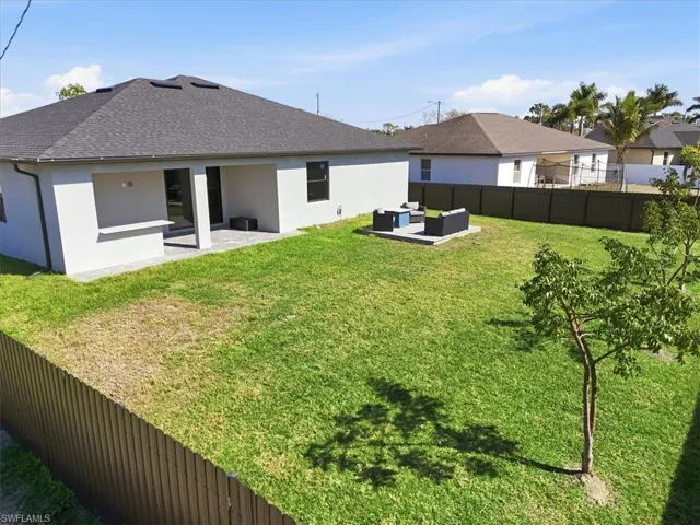 Back of property with outdoor furniture, a patio area, stucco siding, a fenced backyard, and roof with shingles