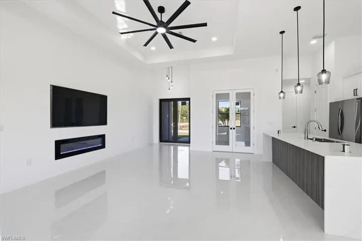 Kitchen with french doors, freestanding refrigerator, light stone countertops, a raised ceiling, and white cabinets