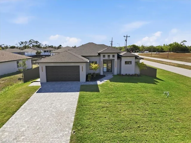Prairie-style home with stucco siding, decorative driveway, an attached garage, and a shingled roof