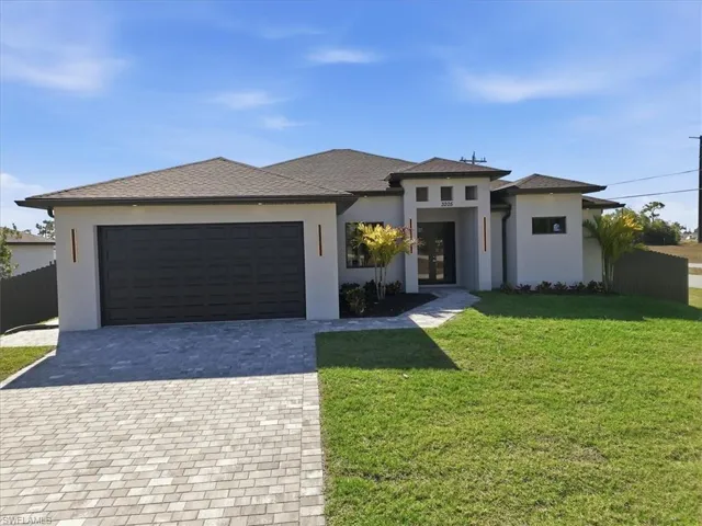Prairie-style home with decorative driveway, stucco siding, a garage, and roof with shingles