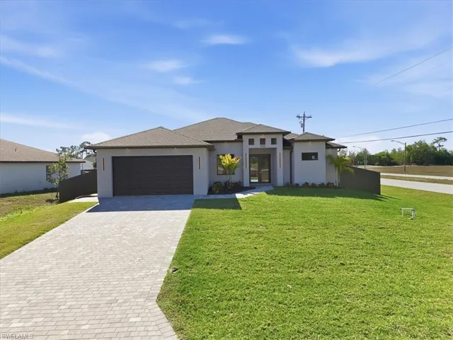 Prairie-style home with stucco siding, a front yard, driveway, and a garage