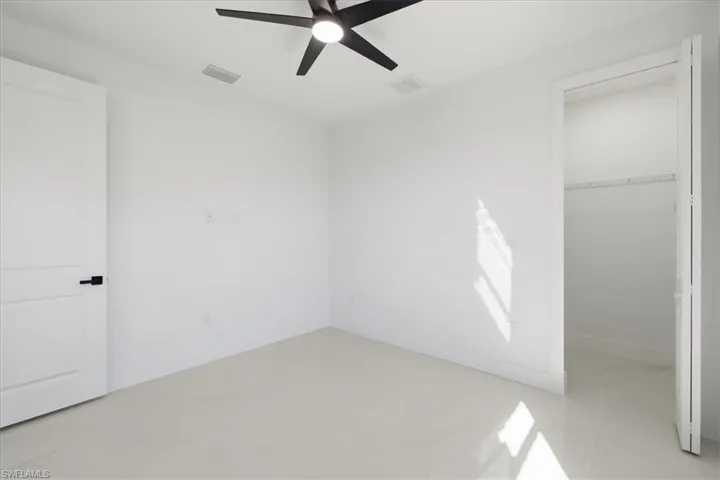Unfurnished bedroom featuring a spacious closet, ceiling fan, and light tile patterned floors