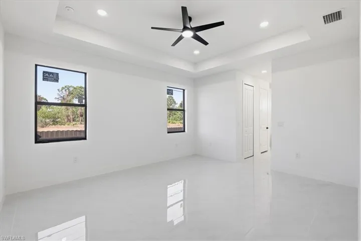 Spare room with a raised ceiling, ceiling fan, and recessed lighting