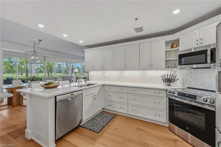 Kitchen with stainless steel appliances, white cabinets, backsplash, recessed lighting, and open shelves