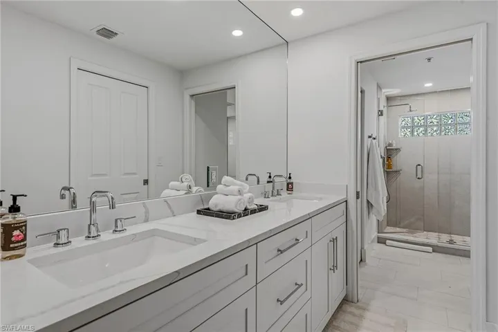 Full bathroom with double vanity, a stall shower, and recessed lighting