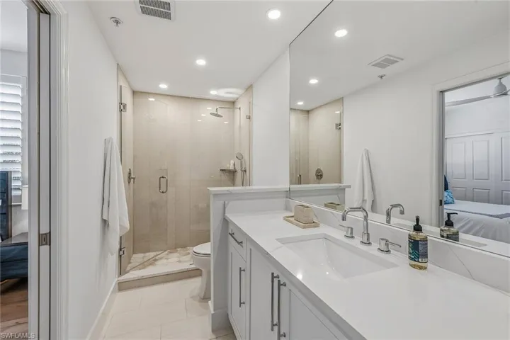 Ensuite bathroom featuring vanity, recessed lighting, a shower stall, and light tile patterned flooring