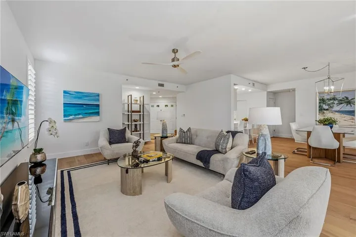 Living room featuring light wood-type flooring, ceiling fan, and a chandelier