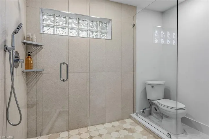 Full bath featuring a shower stall and toilet