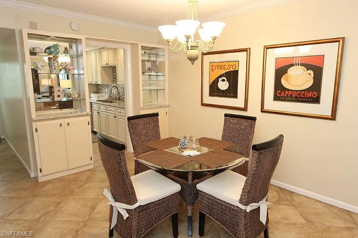 Dining room featuring crown molding, sink, a notable chandelier, and light tile floors